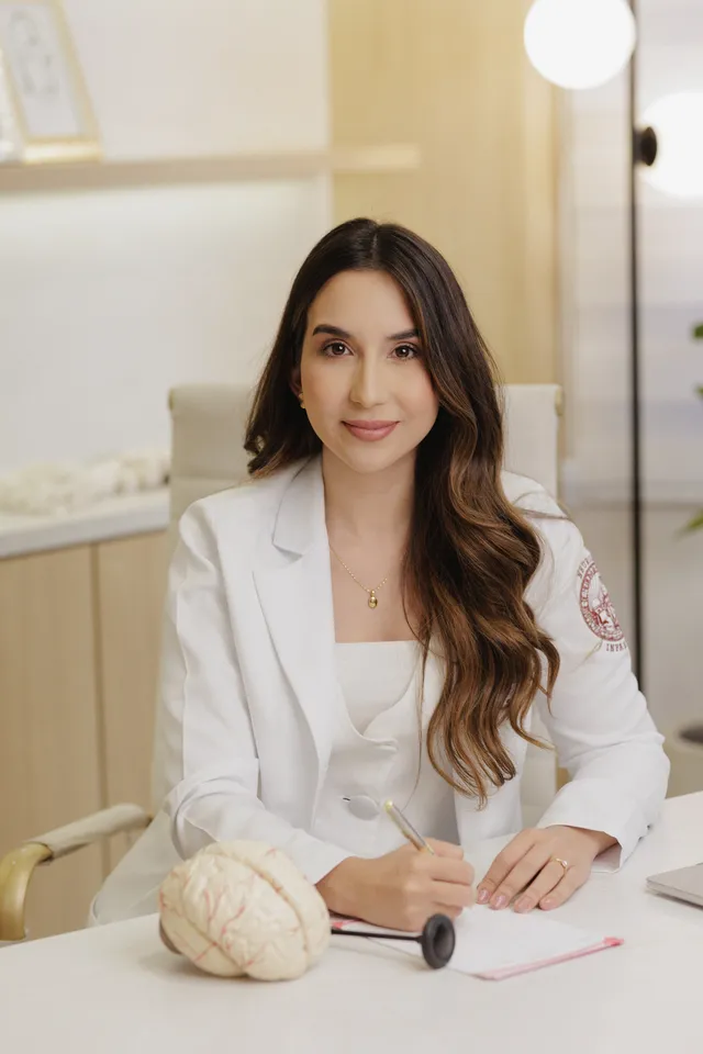 Dra. Samantha Gurgel em seu consultório, ao lado de um modelo do cérebro