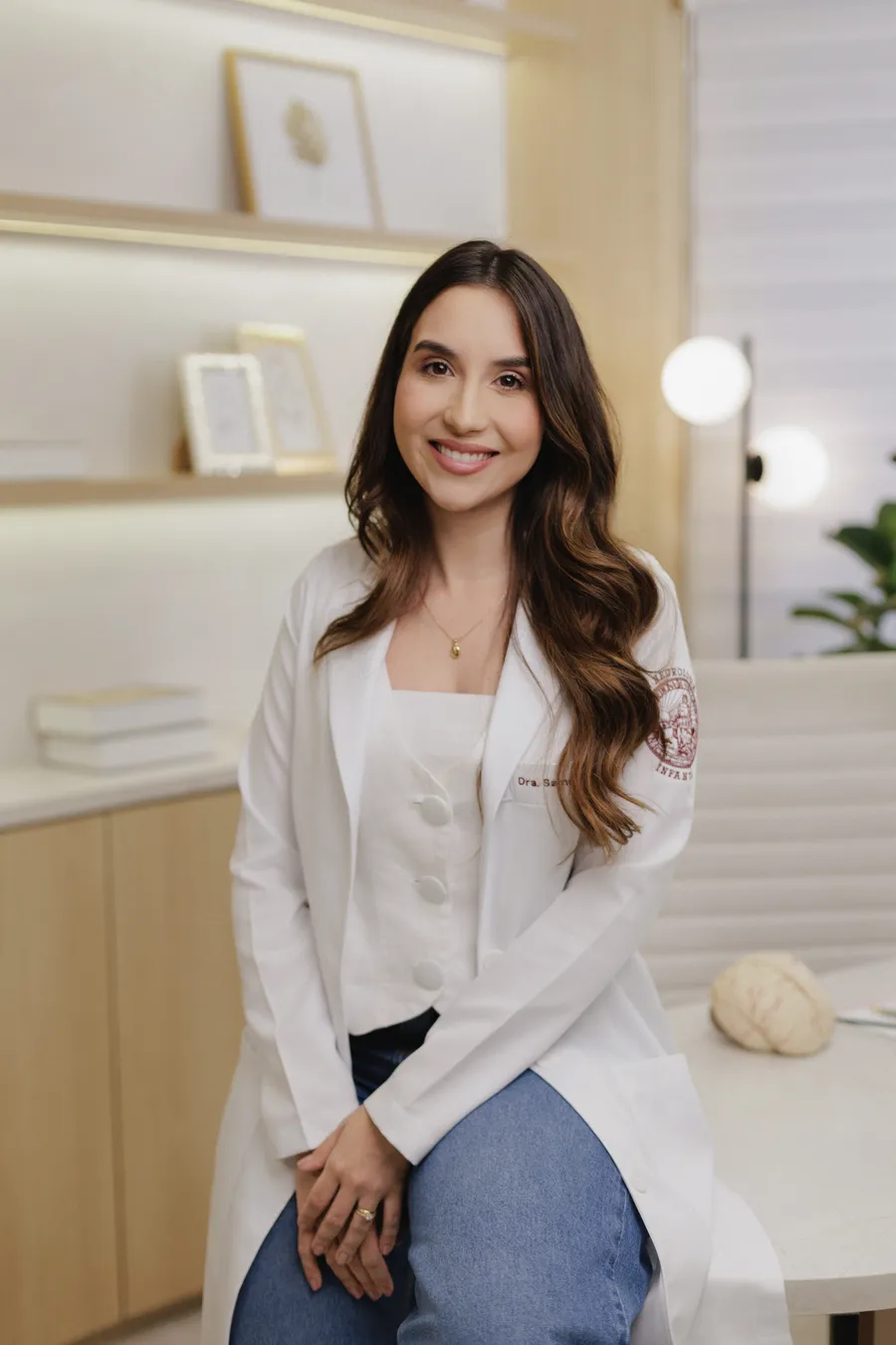 Dra. Samantha Gurgel sorrindo, de jaleco branco, em consultório claro e acolhedor